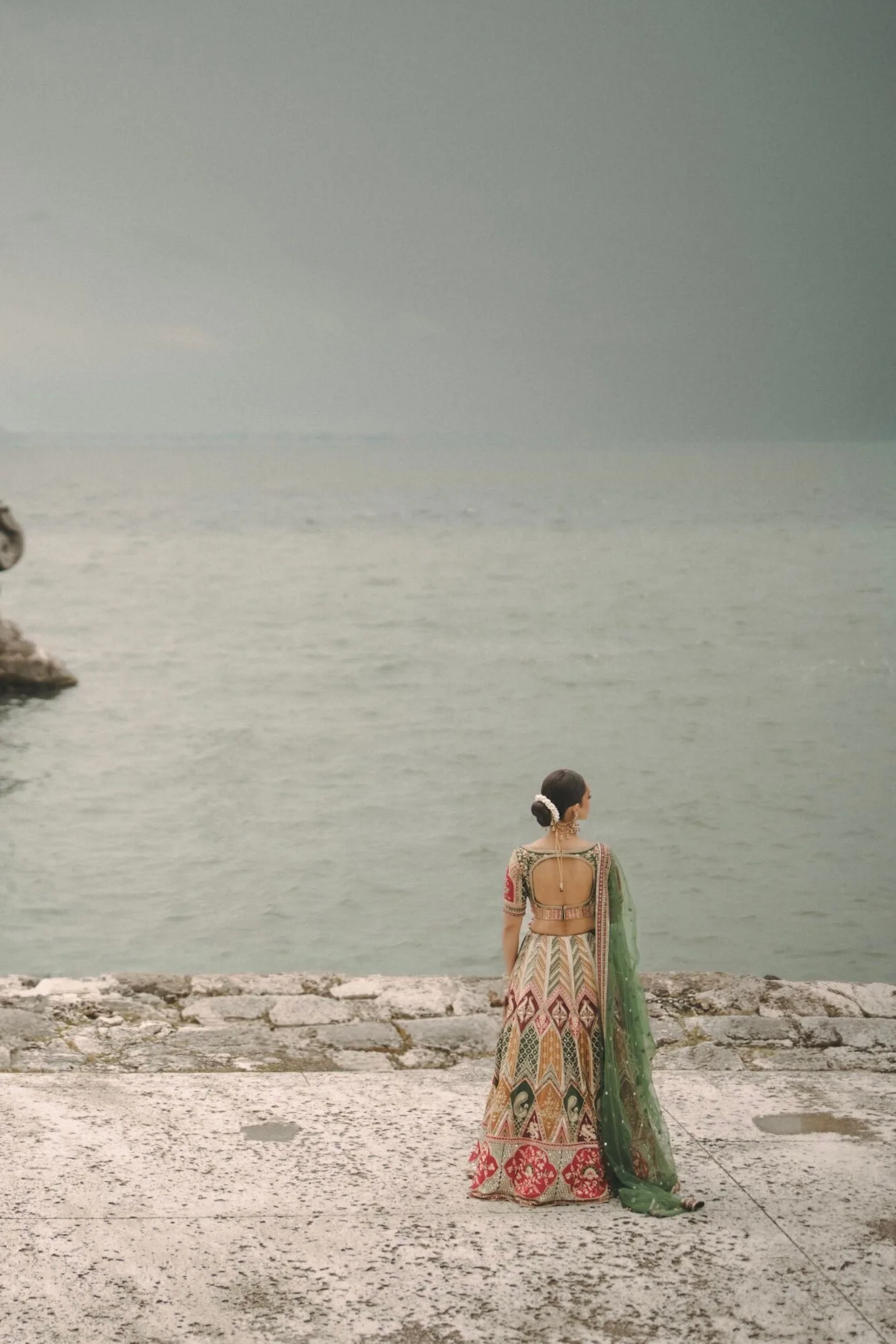 A bride in her lehenga photographed by the water before her wedding