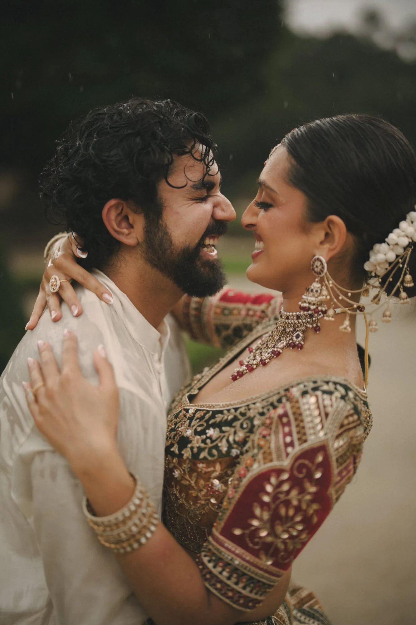 A bride and groom laughing together in the rain after their wedding ceremony