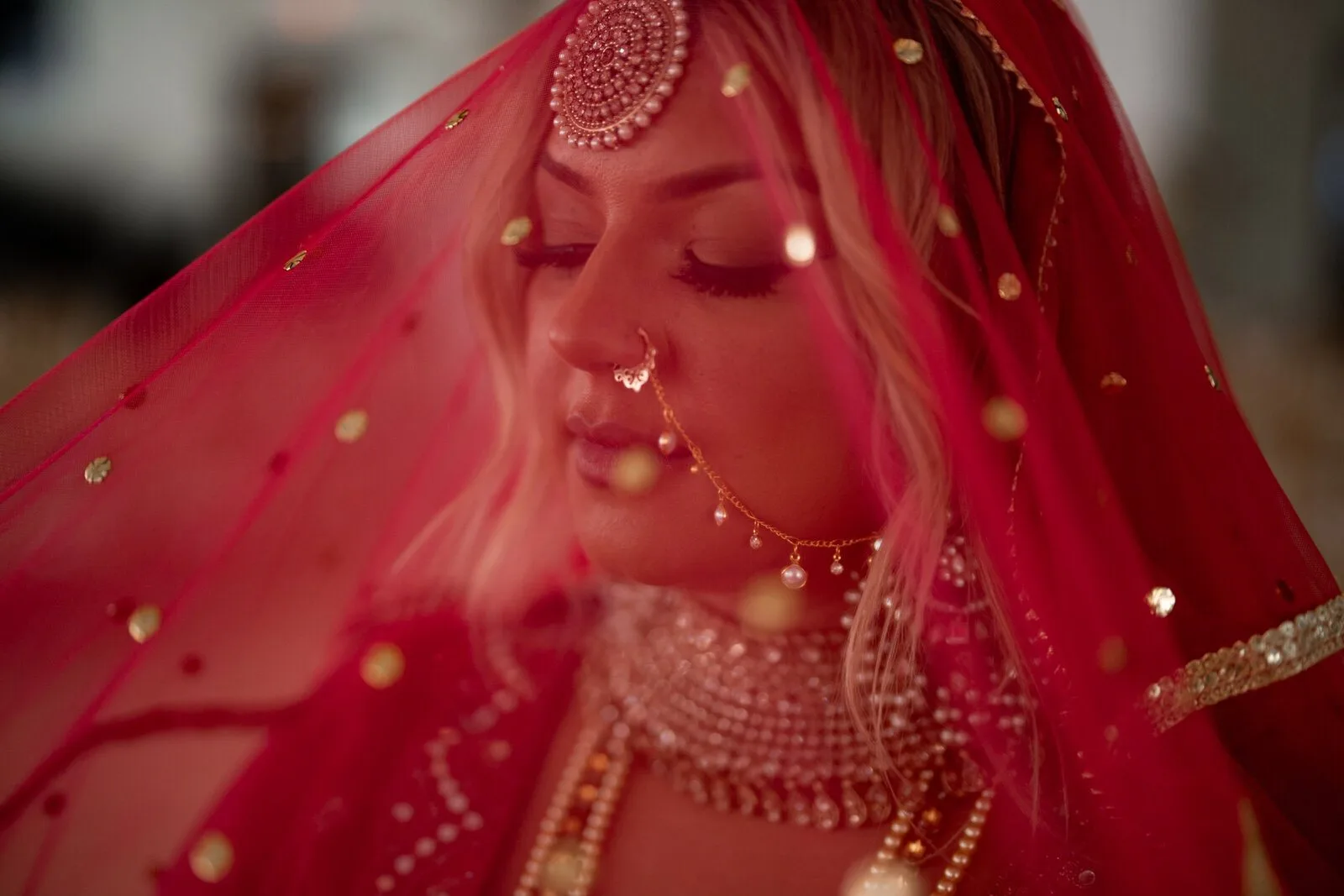 A bride beneath a red and gold veil