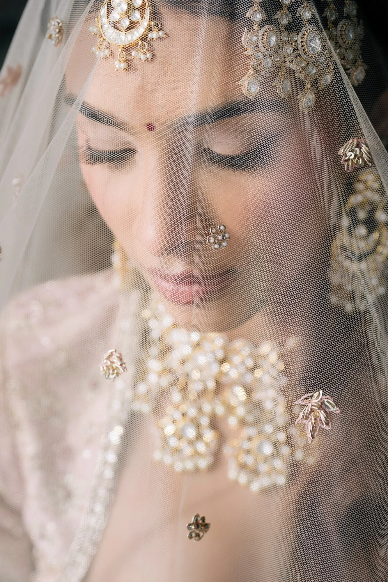 A bride beneath her dupatta, photographed in the minutes before the ceremony